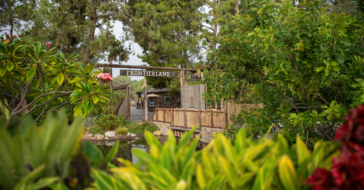 Frontierland entrance sign at Disneyland surrounded by greenery